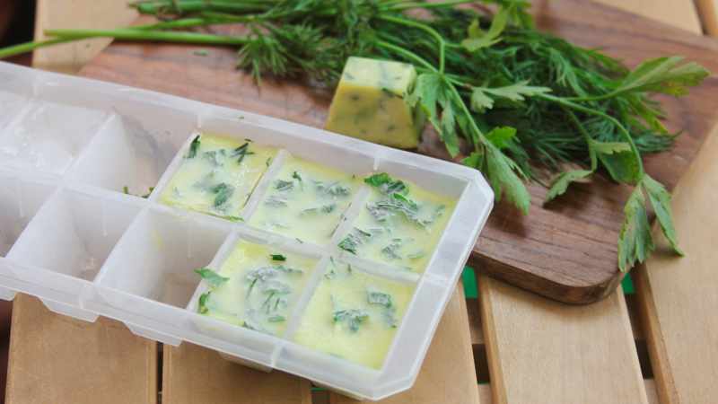 Eiswürfelform mit in Eiswürfeln gefrorenen Kräutern