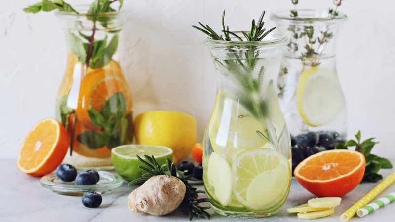 drei WECK-Flaschen mit Limonade und Dekoration aus Obstschreiben und Kräutern